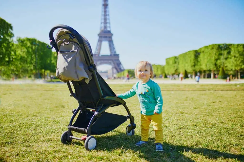 Child with stroller standing near the Eiffel Tower